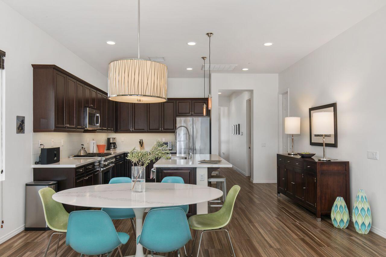 85559 Treviso Drive Indio, CA 92203 - Photo 11 of 30 a kitchen with granite countertop a table chairs a sink dishwasher stove and cabinets
