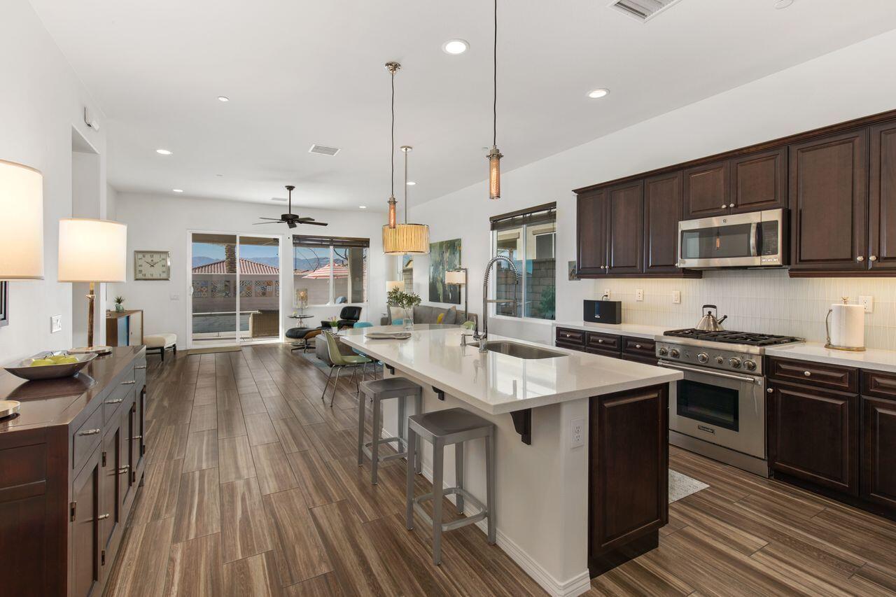 85559 Treviso Drive Indio, CA 92203 - Photo 3 of 30 a kitchen with stainless steel appliances granite countertop a stove a sink dishwasher a microwave oven and a dining table with wooden floor