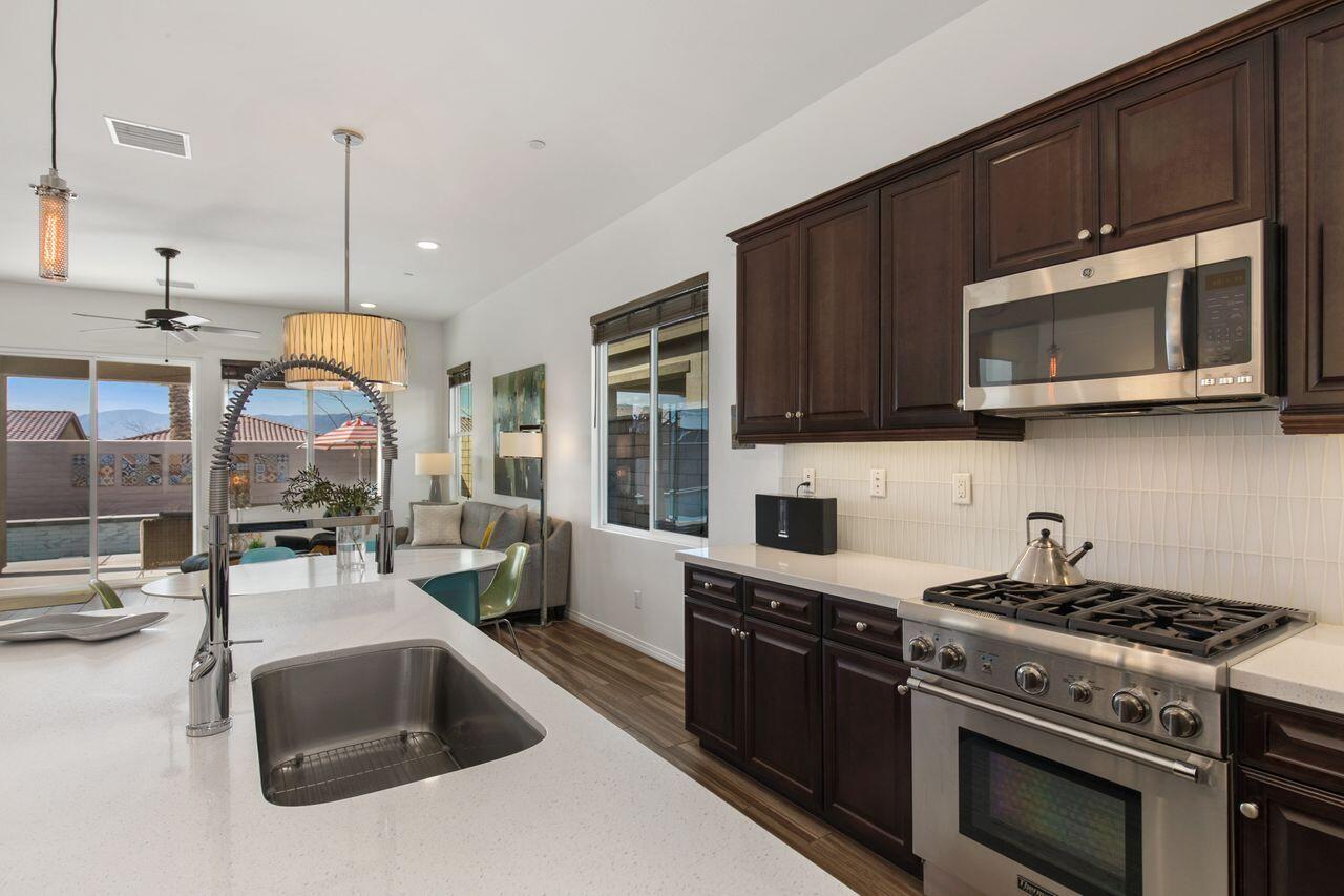 85559 Treviso Drive Indio, CA 92203 - Photo 5 of 30 a kitchen with stainless steel appliances a stove a sink a microwave oven and a refrigerator with wooden floor