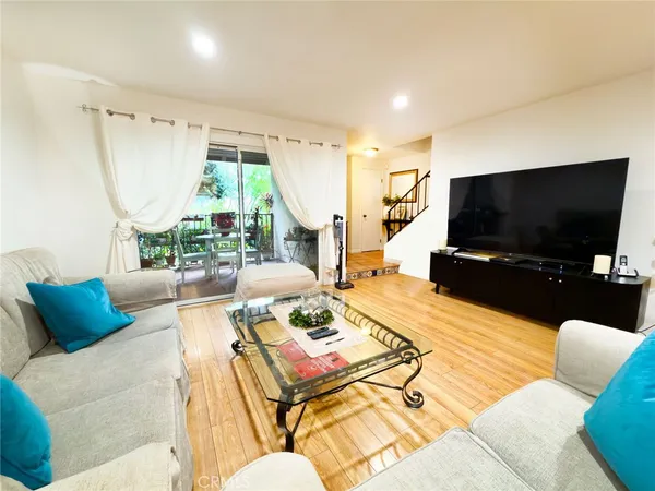 a living room with furniture large window and wooden floor