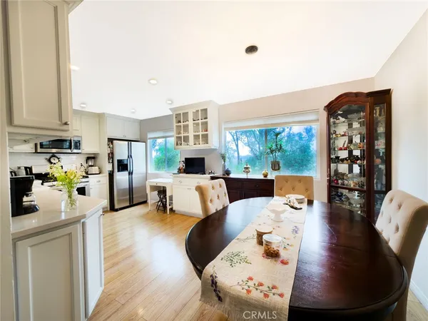 a kitchen with stainless steel appliances a stove top oven a sink a refrigerator white cabinets and wooden floor