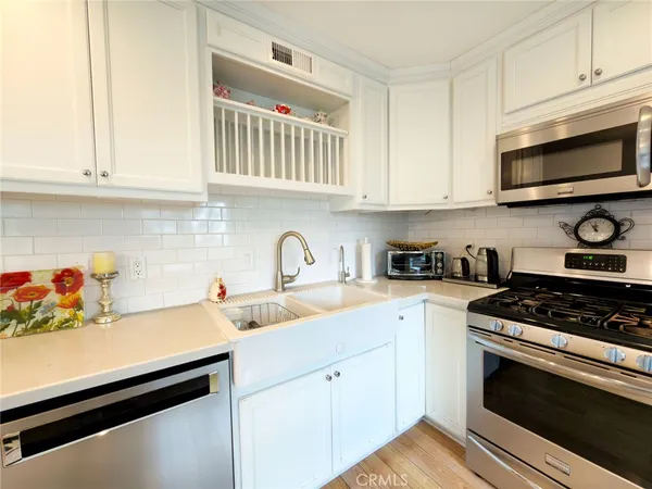 a kitchen with stainless steel appliances granite countertop grey cabinets a stove a sink and dishwasher