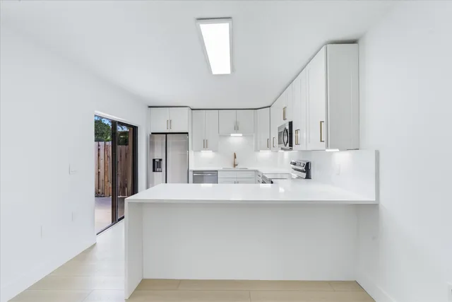 a view of a kitchen with kitchen island a sink wooden floor and refrigerator