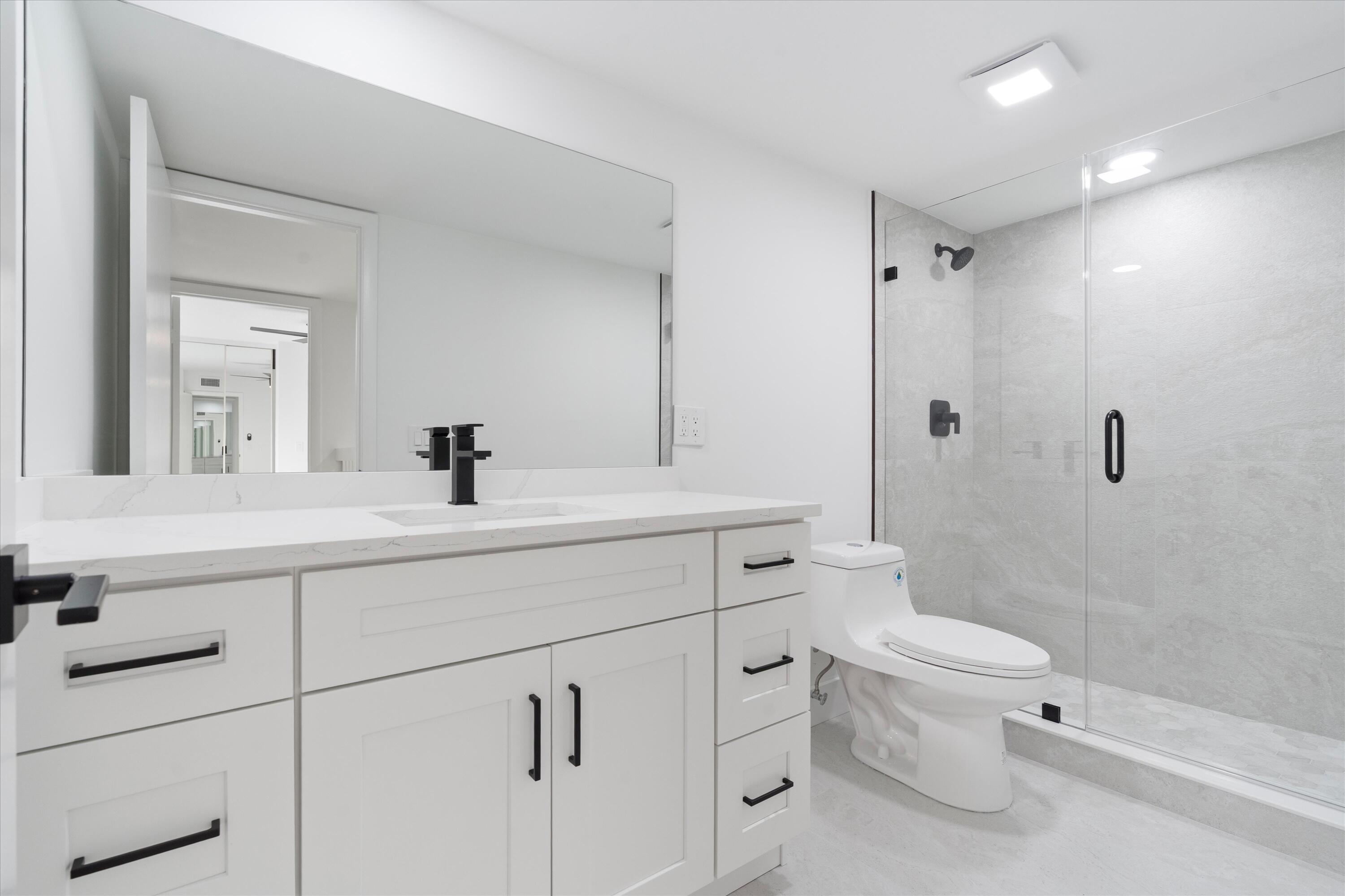 2897 Southwest 22nd Circle, Unit 44B Delray Beach, FL 33445 - Photo 20 of 31 a bathroom with a sink a toilet and shower