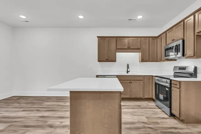 a kitchen with stainless steel appliances a sink dishwasher a stove refrigerator and cabinets with wooden floor