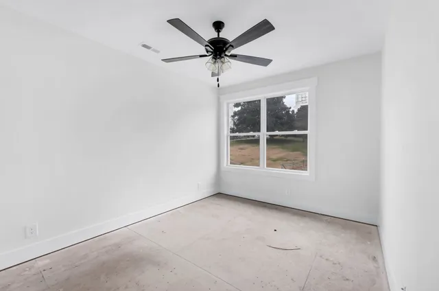 an empty room with windows and fan