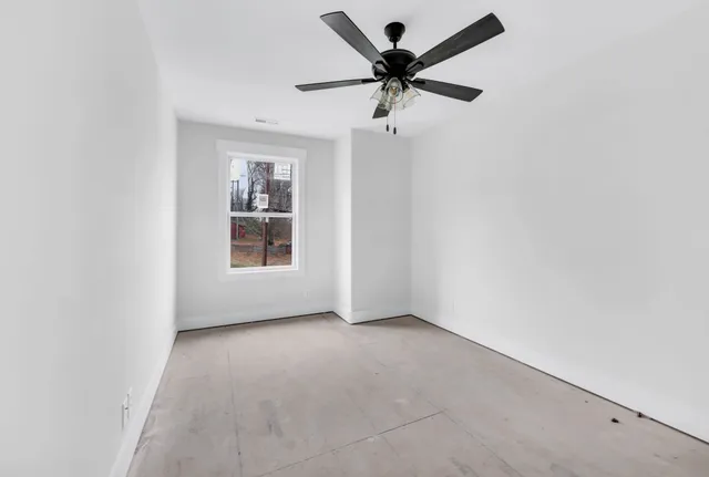 an empty room with a window and a ceiling fan