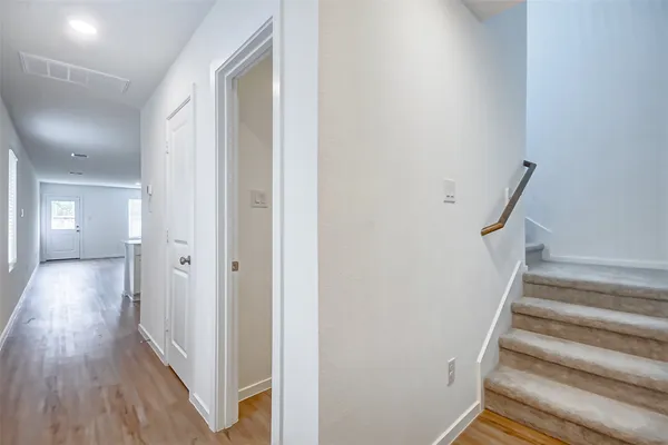 a view of a hallway with wooden floor and staircase
