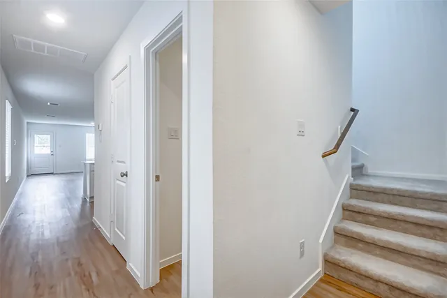 a view of a hallway with wooden floor and staircase