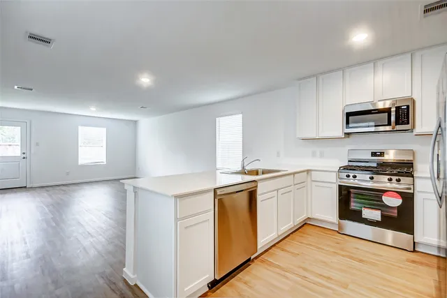 a kitchen with stainless steel appliances granite countertop a stove a sink and a microwave