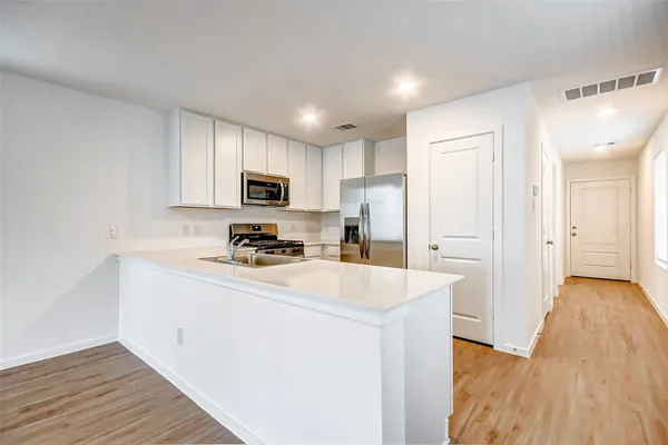 a kitchen with refrigerator cabinets and wooden floor