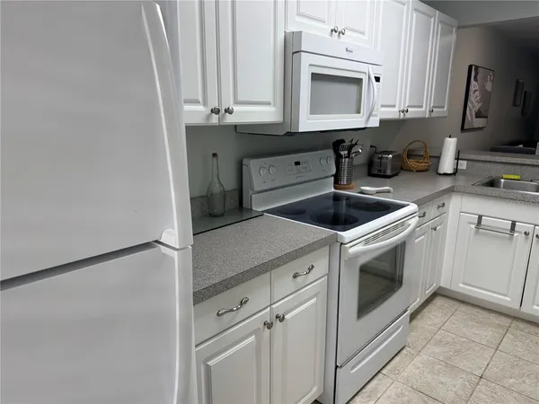 a kitchen with granite countertop white cabinets and white appliances