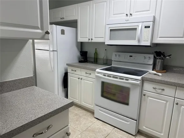 a kitchen with white cabinets and white appliances