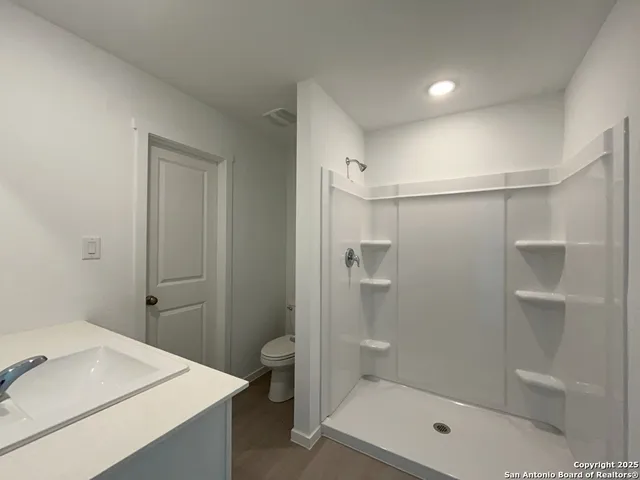 a bathroom with a sink a toilet and shower