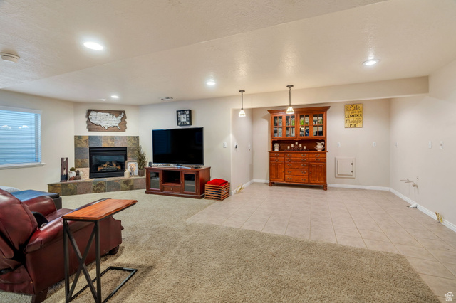 1602 Renaissance Way Springville, UT 84663 - Photo 23 of 42 Living area featuring light tile patterned flooring, a tile fireplace, a textured ceiling, light colored carpet, and recessed lighting