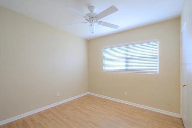 an empty room with a window and a ceiling fan
