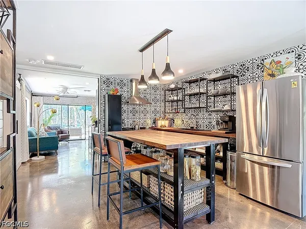 a kitchen with stainless steel appliances granite countertop a table chairs and a refrigerator