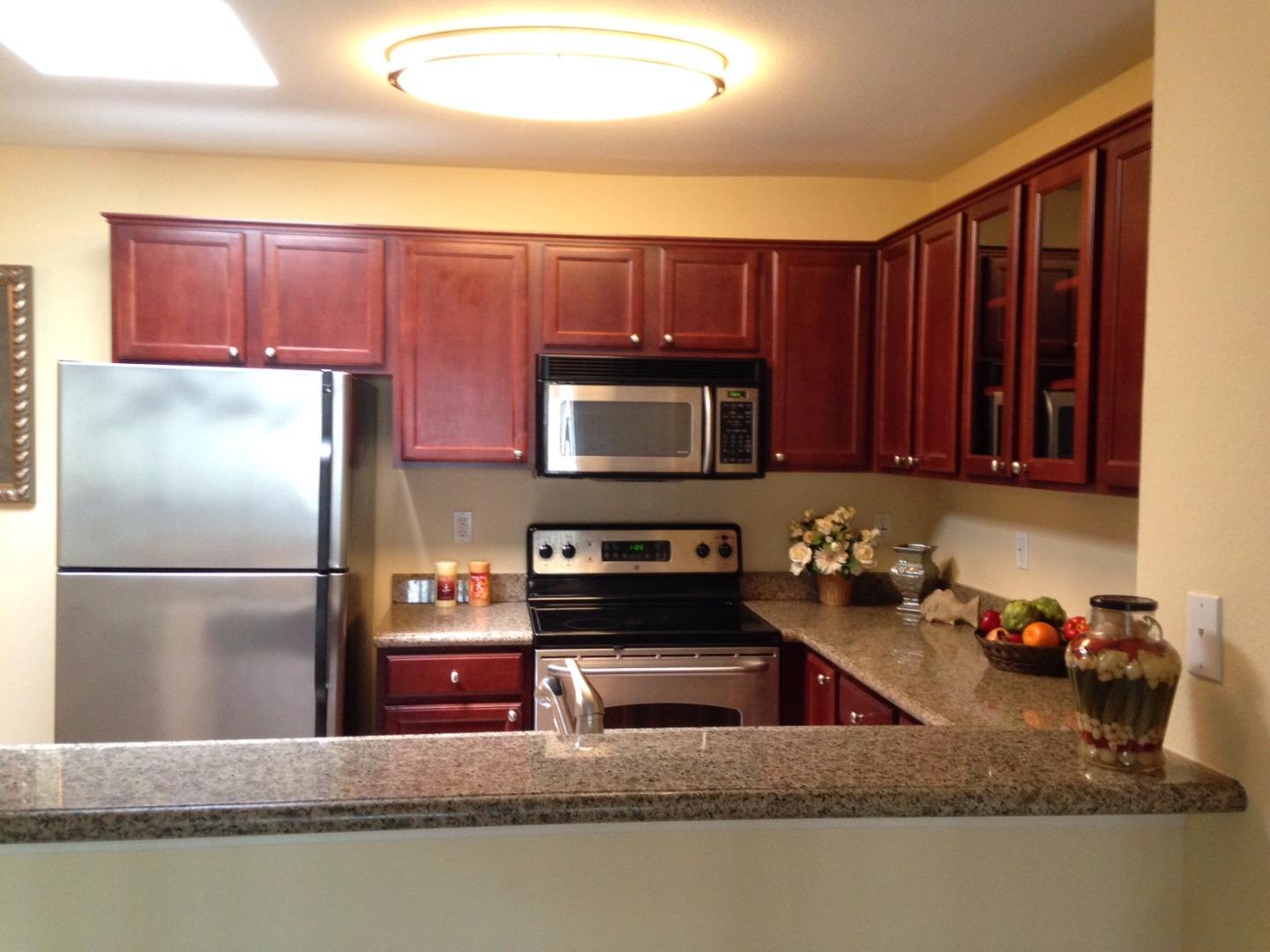 464 Dempsey Road, Unit 265 Milpitas, CA 95035 - Photo 3 of 15 a kitchen with stainless steel appliances granite countertop a refrigerator a stove and a sink with wooden cabinets