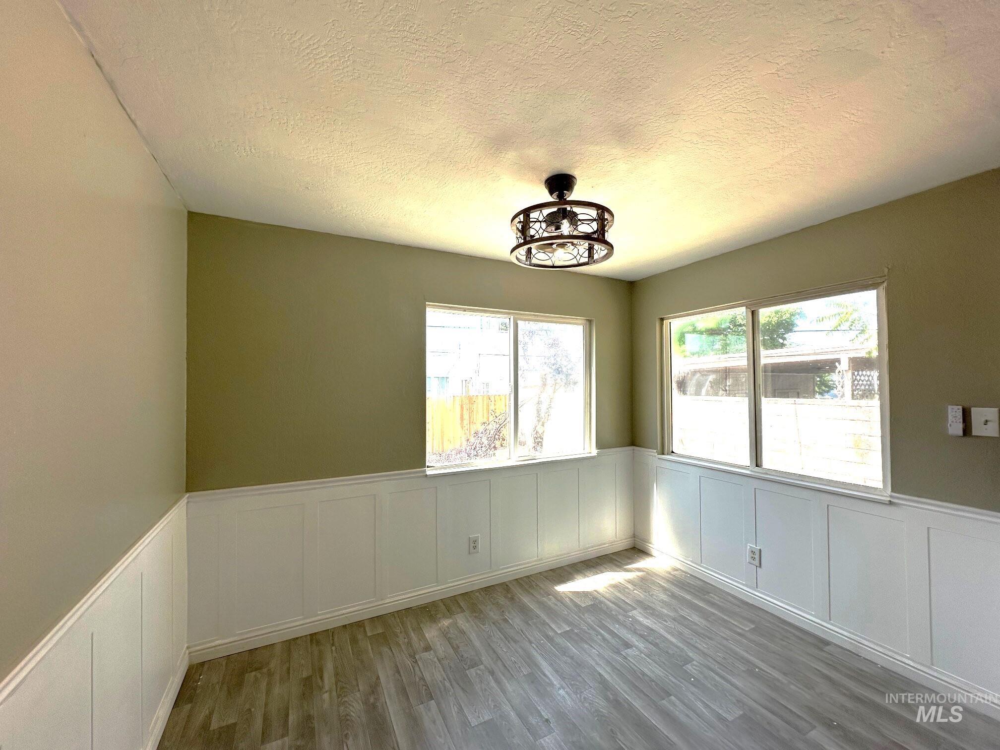 264 Southwest 10th Avenue Ontario, OR 97914 - Photo 8 of 29 Unfurnished dining area with a decorative wall, a textured ceiling, wainscoting, and wood finished floors