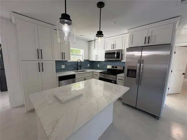 a kitchen with kitchen island a counter top space stainless steel appliances and cabinets