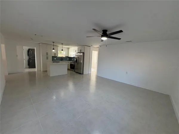 a view of a kitchen with a sink a ceiling fan and stainless steel appliances