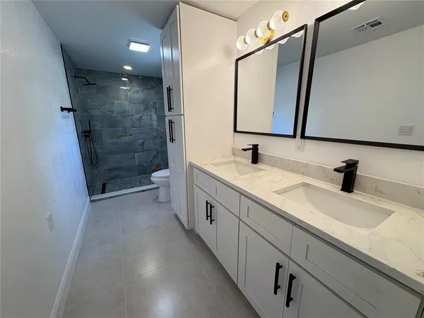 a bathroom with a double vanity sink mirror and shower