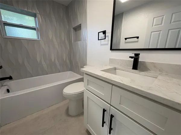 a bathroom with a granite countertop toilet a sink and bathtub