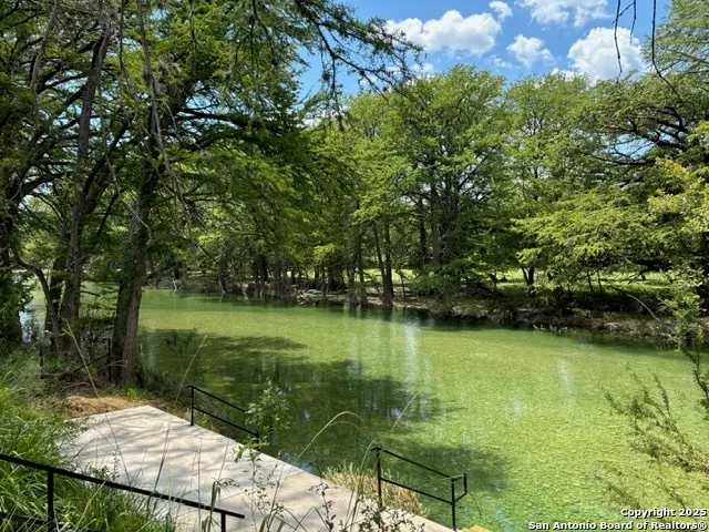 a view of a water pond with green yard