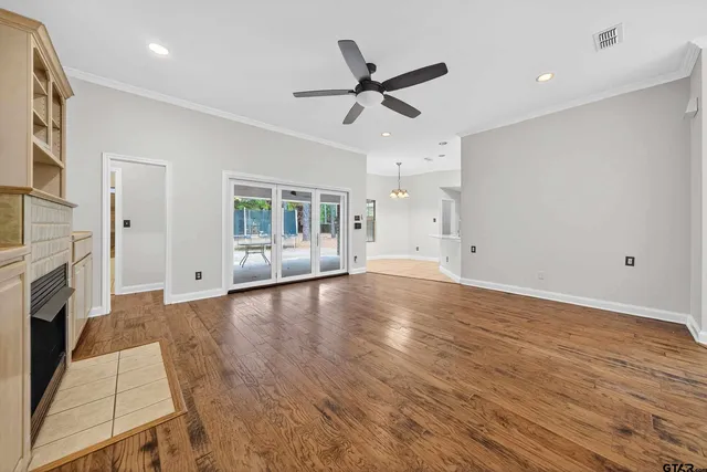 a view of an empty room with wooden floor and a fireplace