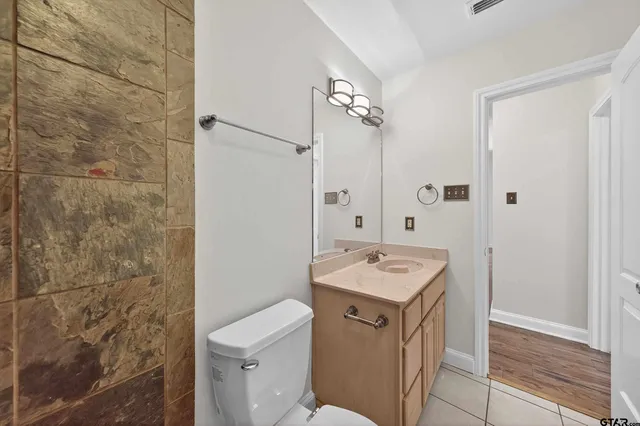 a bathroom with a granite countertop sink a toilet and a shower
