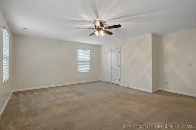 an empty room with windows and fan