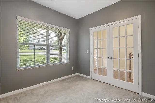 an empty room with windows and fireplace