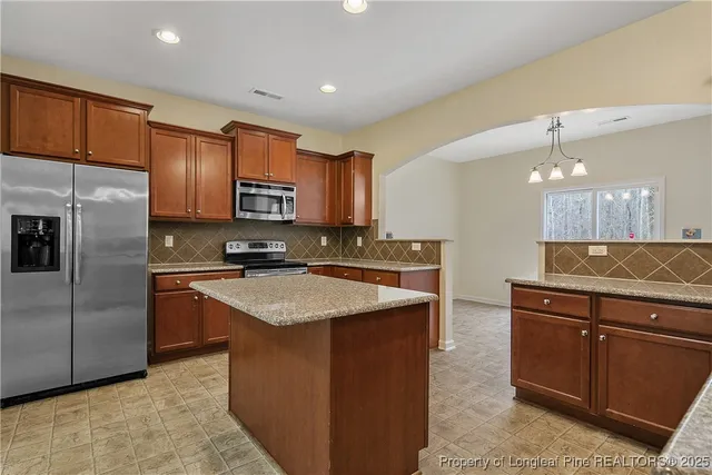 a kitchen with stainless steel appliances granite countertop a stove a refrigerator and a microwave