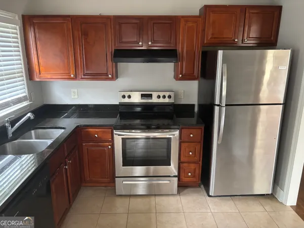 a kitchen with granite countertop a refrigerator stove and cabinets
