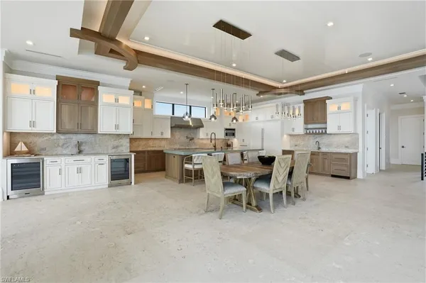a kitchen with stainless steel appliances kitchen island granite countertop lots of white cabinets a stove and chairs