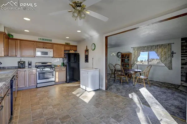 a kitchen with stainless steel appliances a refrigerator a stove a sink a dining table and chairs with wooden floor