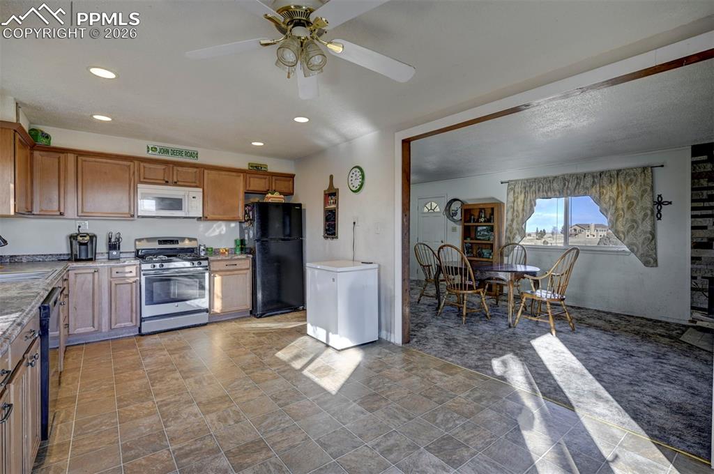 9420 Mulberry Road Calhan, CO 80808 - Photo 6 of 49 a kitchen with stainless steel appliances a refrigerator a stove a sink a dining table and chairs with wooden floor