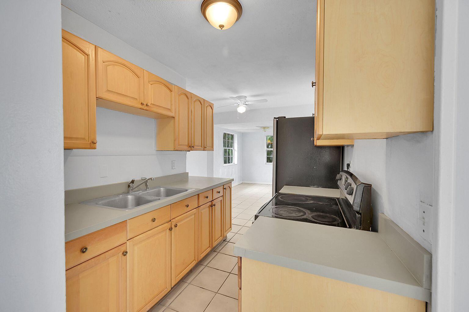 1645 West 31st Street Riviera Beach, FL 33404 - Photo 3 of 20 a kitchen with granite countertop a sink a stove and a wooden cabinets