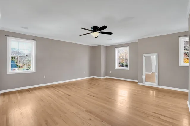 a view of an empty room with window and wooden floor