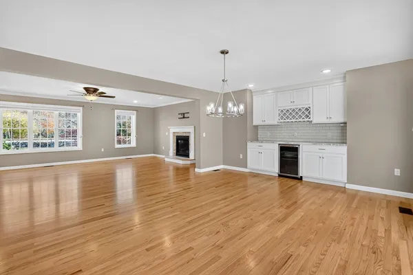a view of empty room with wooden floor and kitchen view
