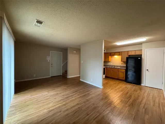 a view of an empty room with kitchen and a window