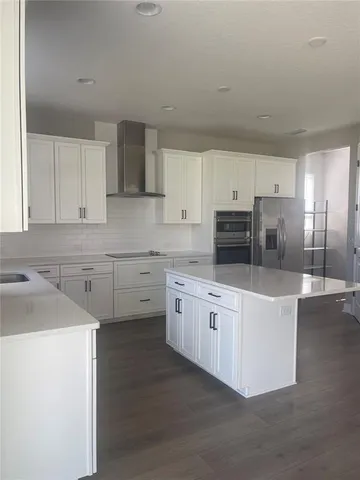 a kitchen with stainless steel appliances white cabinets a sink a stove a refrigerator and white cabinets