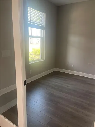 an empty room with wooden floor and windows