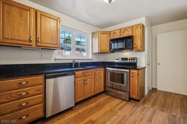 a kitchen with granite countertop wooden cabinets stainless steel appliances and a window