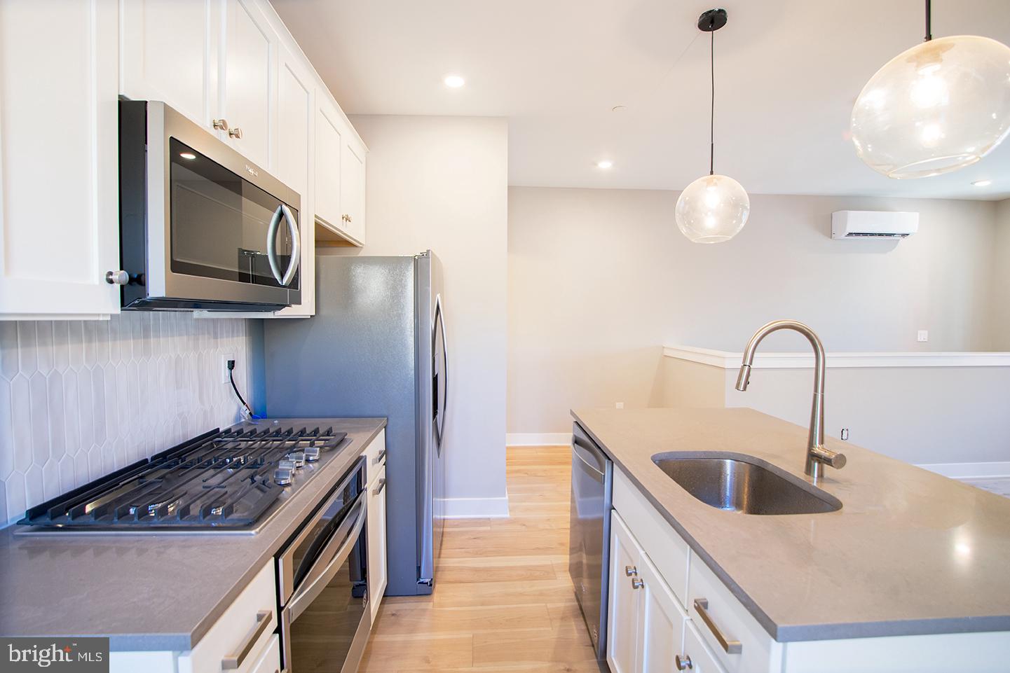129 South 49th Street, Unit 1F Philadelphia, PA 19139 - Photo 3 of 18 a kitchen with stainless steel appliances granite countertop a sink a stove and a wooden cabinets
