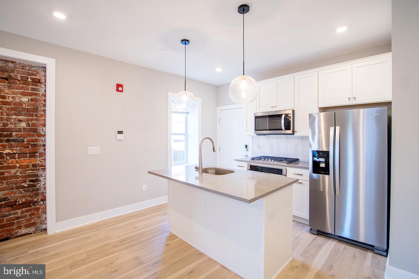 129 South 49th Street, Unit 1F Philadelphia, PA 19139 - Photo 4 of 18 a kitchen with stainless steel appliances granite countertop a refrigerator a sink dishwasher a stove and a wooden floor