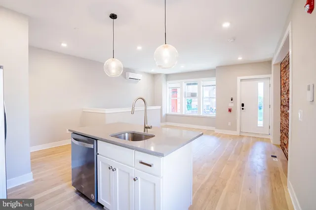 a kitchen with stainless steel appliances granite countertop a sink a window and wooden floor