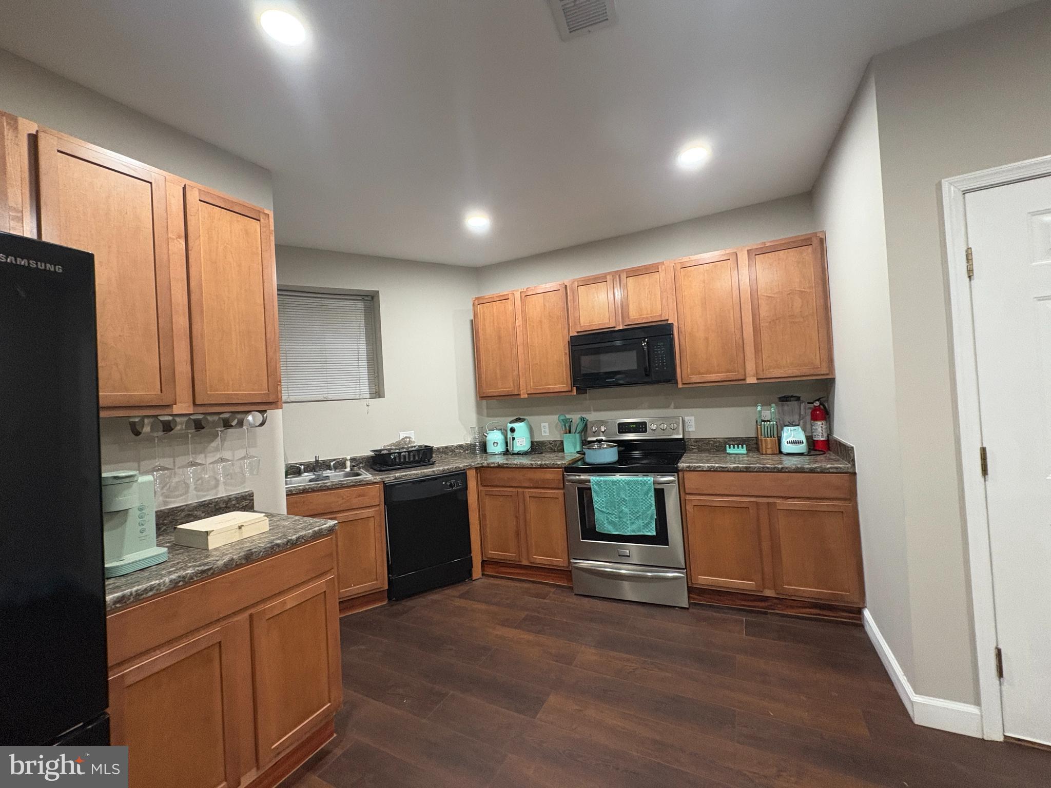 222 North Liberty Street, Unit 2 Baltimore, MD 21201 - Photo 4 of 15 a kitchen with stainless steel appliances granite countertop refrigerator a stove top oven a sink and dishwasher with wooden floor