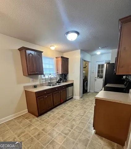 a large kitchen with stainless steel appliances a stove a sink dishwasher and a refrigerator