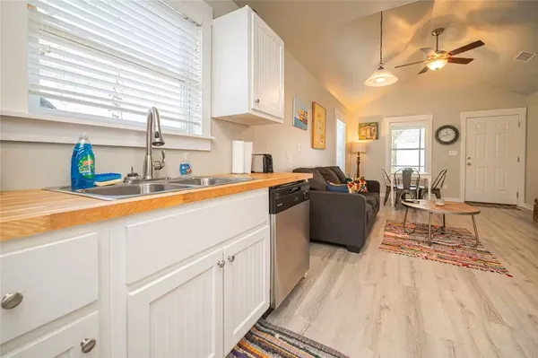 a kitchen with stainless steel appliances a stove a sink a refrigerator white cabinets and couches with wooden floor